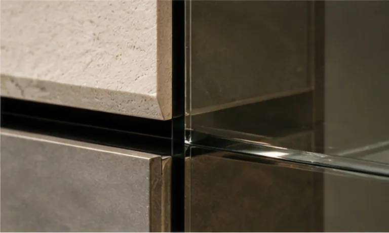 Travertine, patinated bronze and glass meeting at a corner junction